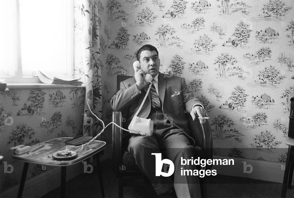 Ronnie Kray one of the Kray twins, pictured sitting at home after helping police inquiries into the Blind Beggar Pub shooting, London, 6th August 1966 (b/w photo)