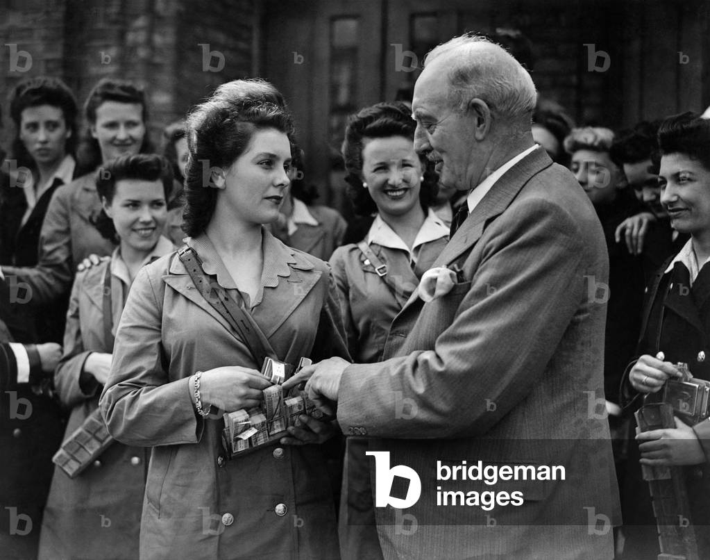 World War II Women: 19 years old Olivia Clark of Kew Ex Night Club Hostess, is being shown the correct way to punch a ticket. At the London Transport School for conductresses by WD Batchalor, Chief Instructor at the school. May 1944