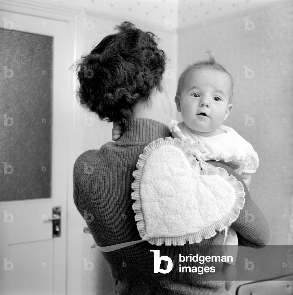 Mother and baby with heart shaped bib, 1961 (b/w photo)