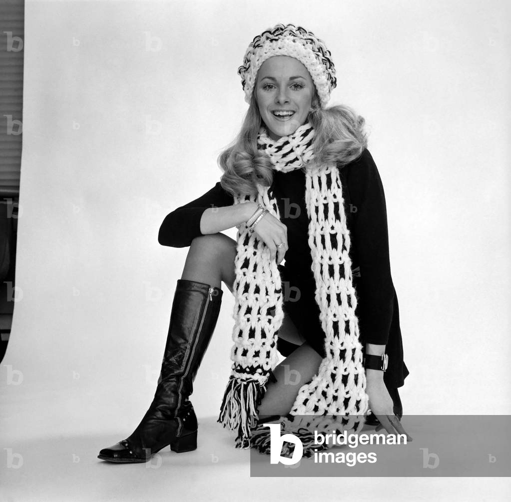 Model: 21 year old Carole Roddick. Pictures of Carole taken in the studio wearing crocheted scarf and hat, maxi coat and knee high leather boots. December 1969