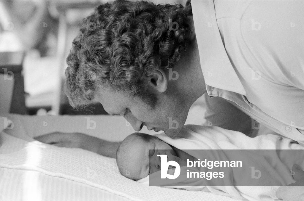 Former British European Heavyweight champion boxer Joe Bugner kisses his new born baby son Lajos James after his birth at Hill Road Maternity Hospital in Cambridge. 16th May 1976 (b/w photo)