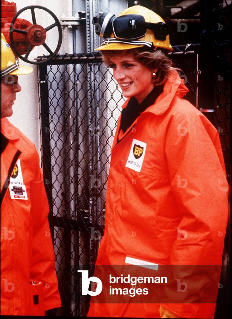 Princess Diana on the north sea oil rig - Diana is wearing a construction hard hat with protective ear guards and an orange over coat, September 1985 (photo)