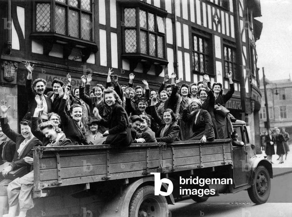 Women munition workers waving cheerfully as they move away to their factory on an army lorry when the South Yorkshire train strike left them stranded, 14th May 1943 (b/w photo)