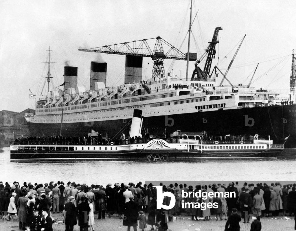 The Cunard White Star ocean liner Queen Mary in the Clyde. Crowds on shore as the Clyde Paddle steamer Eagle III passing the Queen Mary laden with sightseers for a 'last look', 22nd March 1936 (b/w photo)
