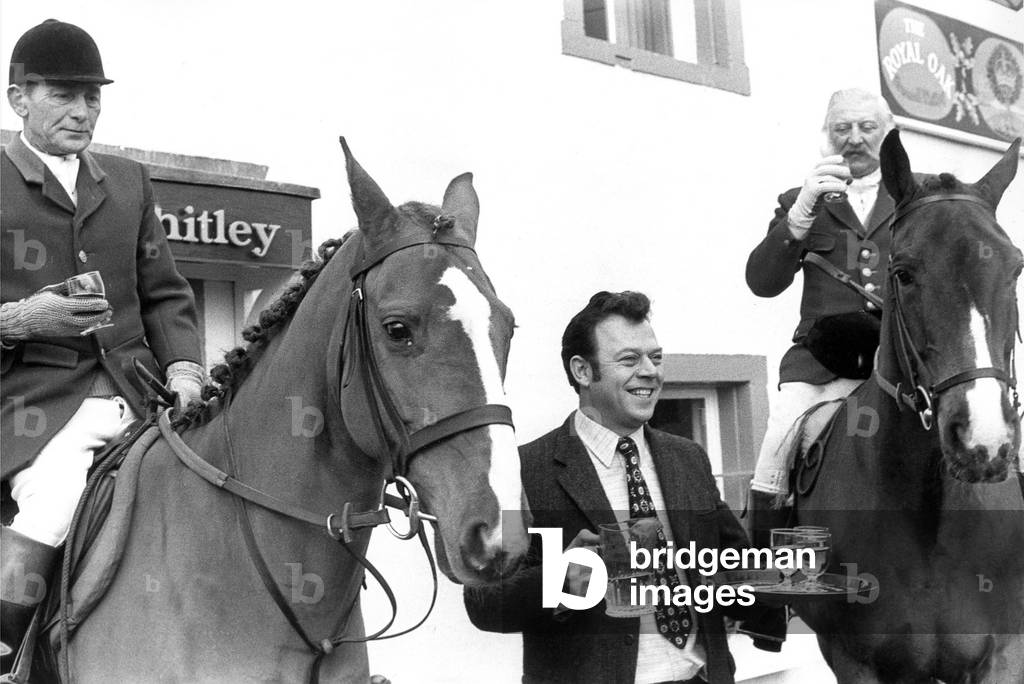 Members of a local hunt having a quick drink to take the chill off before the hunt in November 1976 (b/w photo)