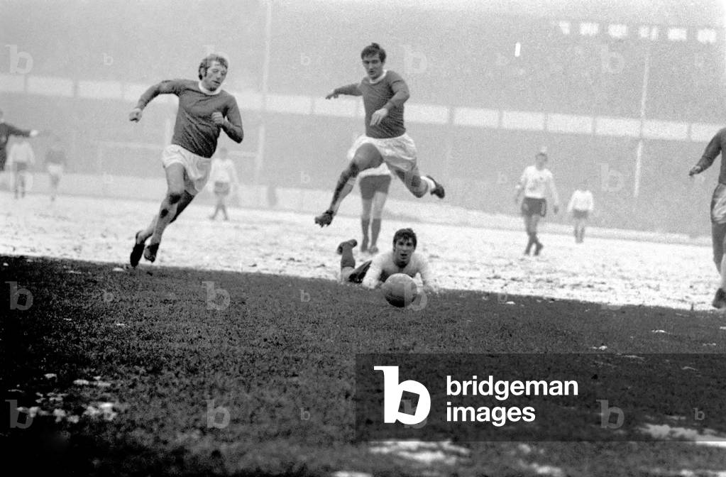 English League Division One match. Everton v. Derby. High flying by Everton's John Hurst as he leaps over Kevin Hector for new signing Keith Newton to clear. The final score was a one nil victory for Everton. December 1969 (photo)