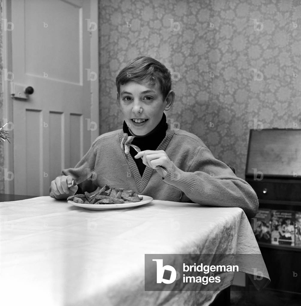 15-year-old Robert Lane of Wheatley Hall Road, Doncaster tried to join the Royal Navy and was told to grow 10 inches and put on a stone. 
Robert is pictured eating his favourite meal - chips. December 1969