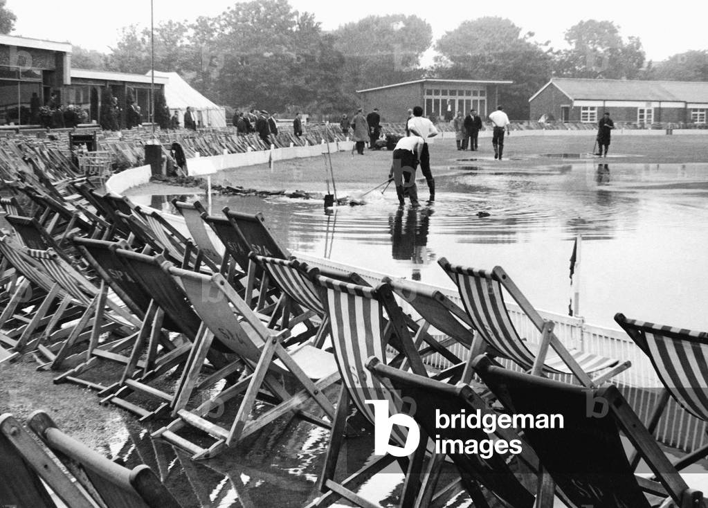 Floods stop play at the Lancashire v. Kent Cricket match at Southport. Ground staff and players trying to dry the pitch out. 15th July 1967 (b/w photo)