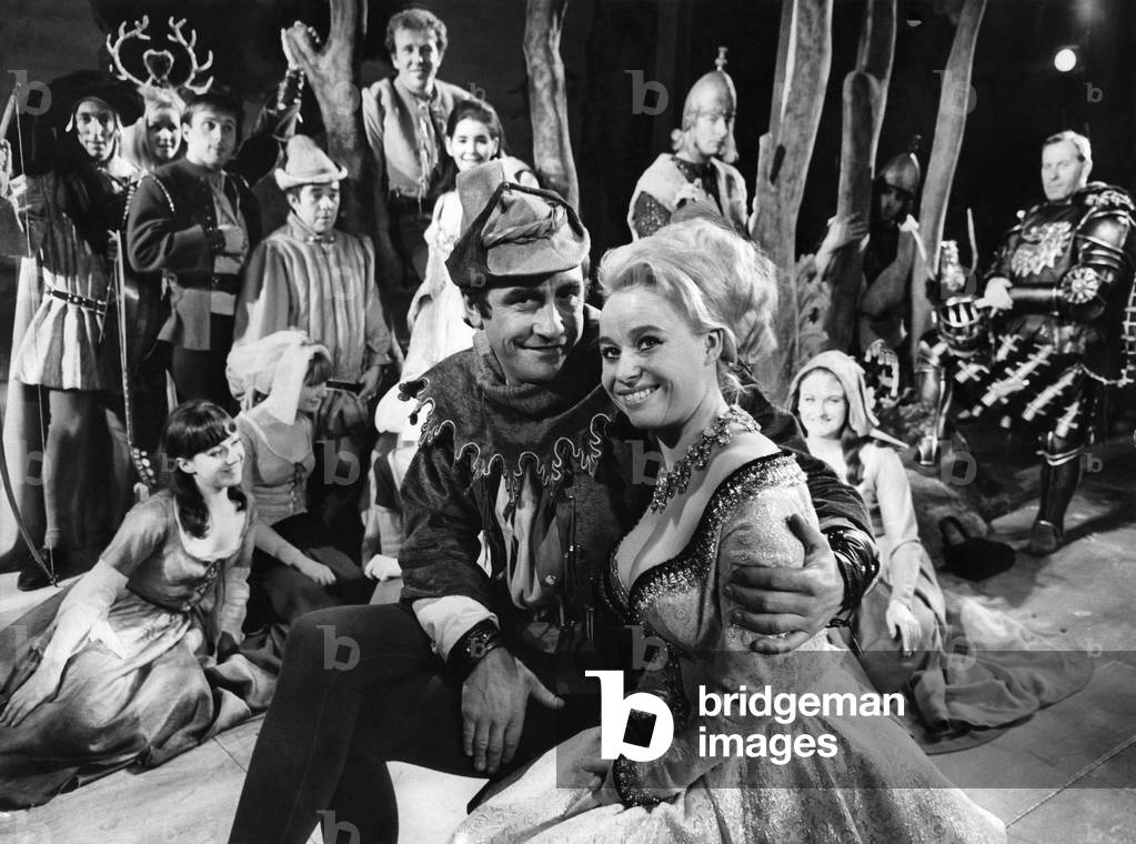 Barbara Windsor who plays Delphina, a lady-in-waiting to Maid Marion and James Booth (Robin Hood) all smiles for the opening of the Lionel Bart musical with a background of cast members at the Palace today. 
November 1965
