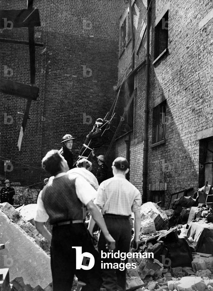 When a building was hit in a raid on this country firemen lowered an injured man from the roof after they had rescued him from the debris. He was taken to hospital. January 1944
