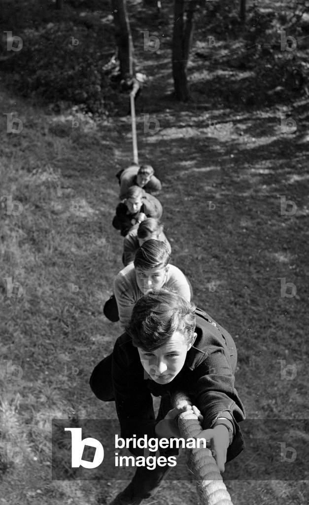 Boys climbing up a rope at the Outward Bound Sea School at Aberdovey Wales. The boys are training to climb the rigging for when they board the school's schooner, 1947 (b/w photo)