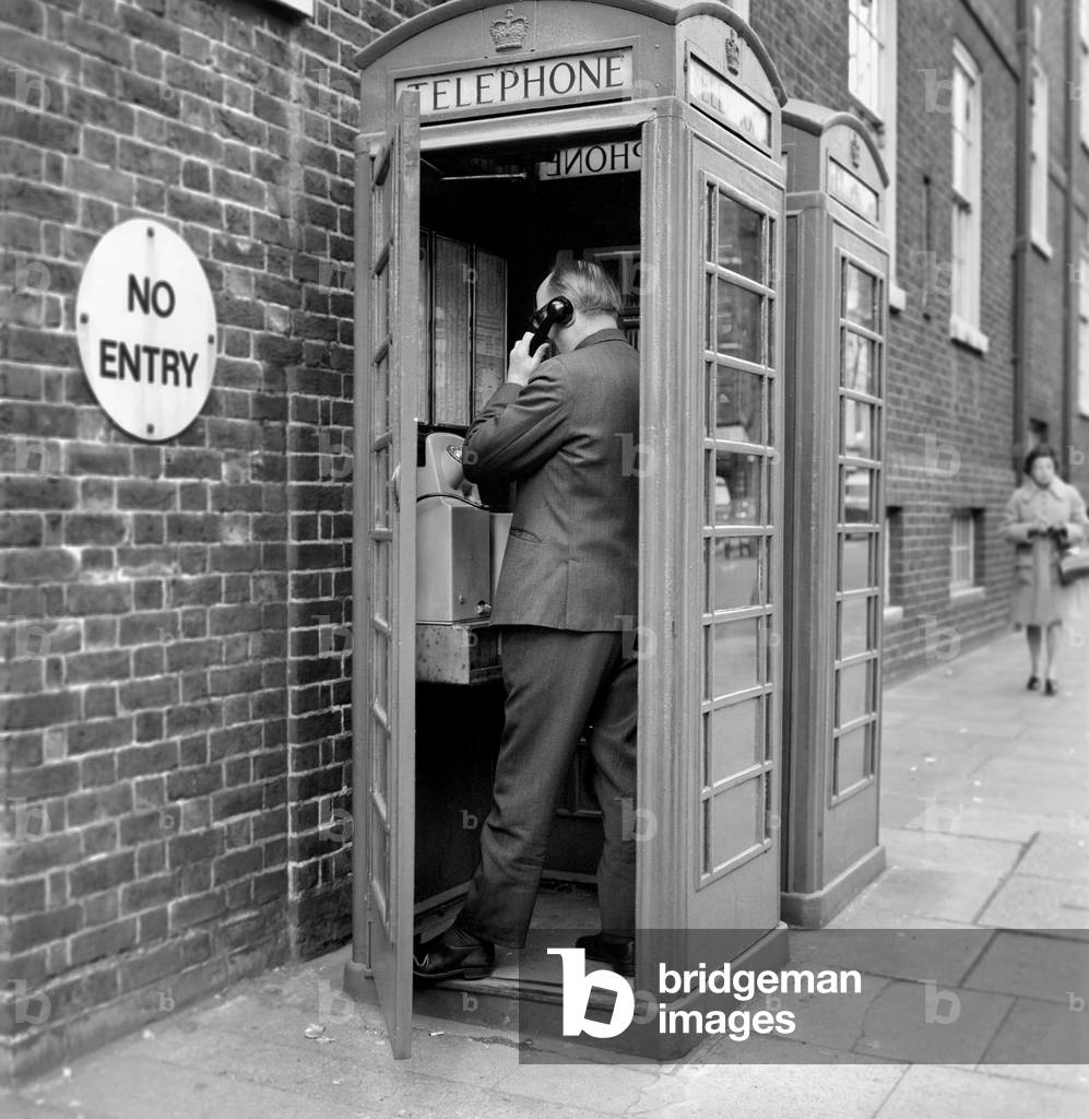 Man using a telephone box, April 1975 (b/w photo)