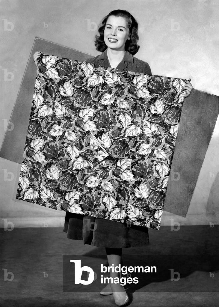 Clothing Beachwear. 
Woman holds example of leaf print. 
August 1956
