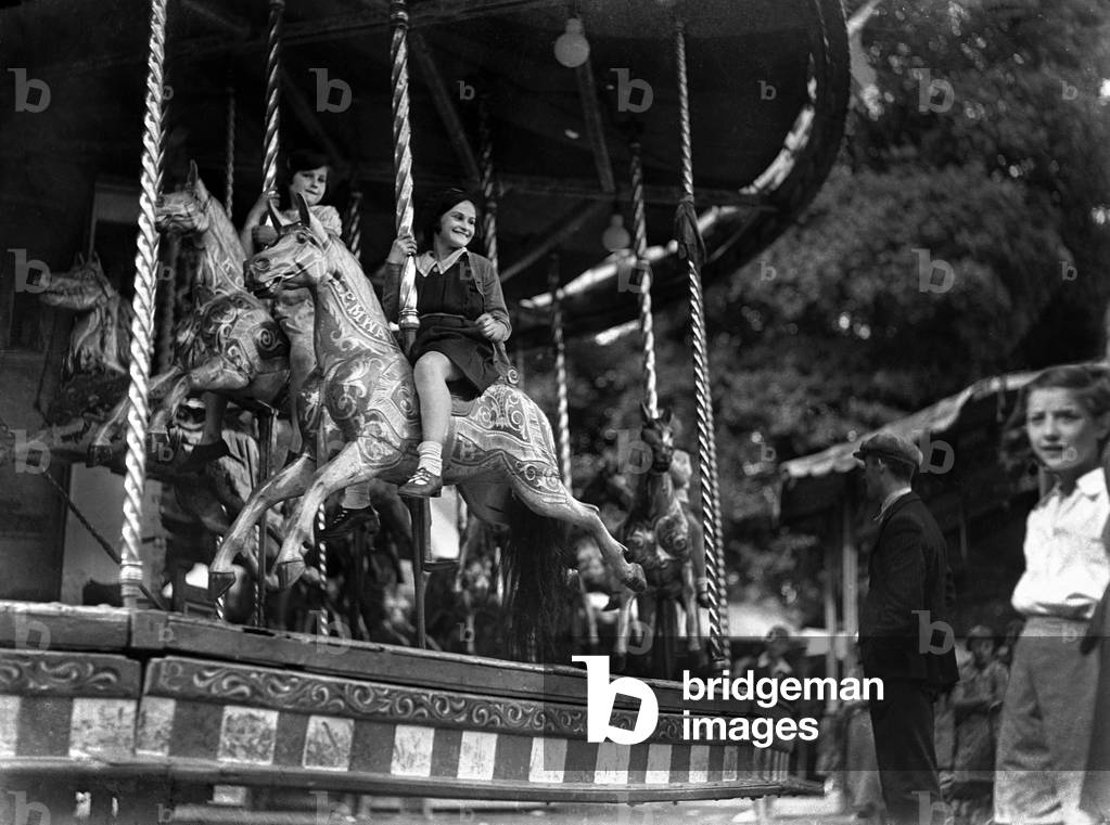 Children ride the Merry-Go-Round at the Surbiton fair. Circa 1930
