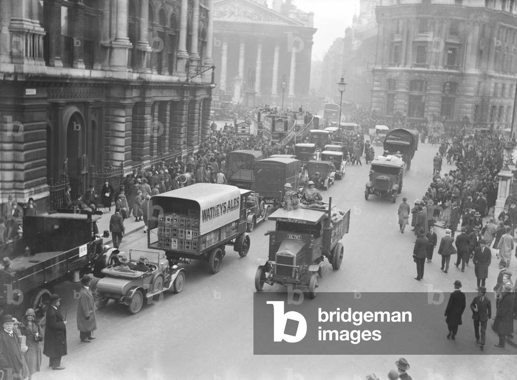 The army escort a food convoy past commuters making their way to work near The Bank in the City of London, on the 9th day of the General Strike. The national dispute came about after negotiations between the miners and mine owners failed over wages and the strike began on 3 May 1926. Millions obeyed the strike call, bringing transport systems to a halt while newspapers were not printed. The government responding by using volunteers to run trains and buses and sent in troops to move supplies from the London docks. There were clashes between police and crowds in many areas and at least 4000 strikers were arrested. There were attacks on buses and trains, including the derailing of the Flying Scotsman. The strike was called off unilaterally by the TUC on 12 May with no guarantees of fair treatment for the miners who fought on to bitter defeat in October. 11th May 1926 (b/w photo)