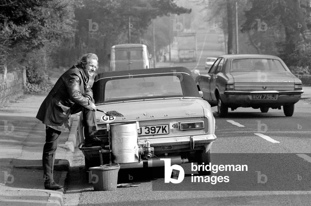 Mr. Douglas Purser who runs his Ford 1,600 c.c. Capri on Coal, shovelling anthracite into the burner, 28th February 1975 (b/w photo)