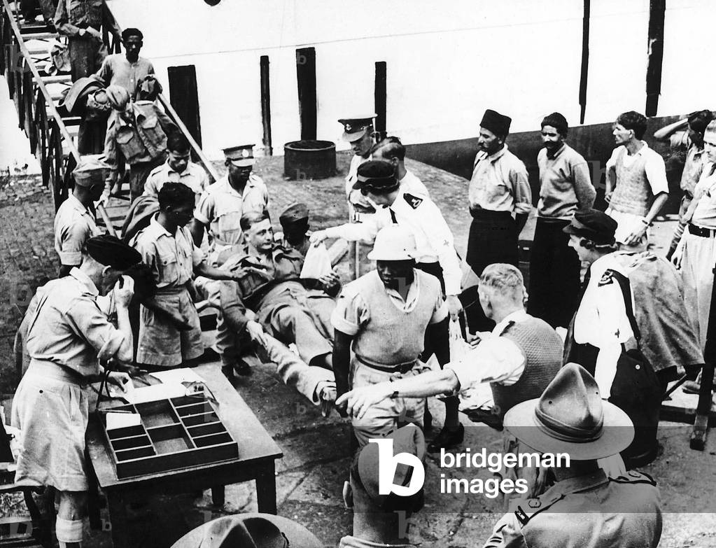 Red Cross & St John's ambulance workers welcome Allied P.O.Ws back to Egypt after their liberation from enemy camps. The soldiers are given cigarettes and bags of sweets by the welcoming helpers. WW2 1943