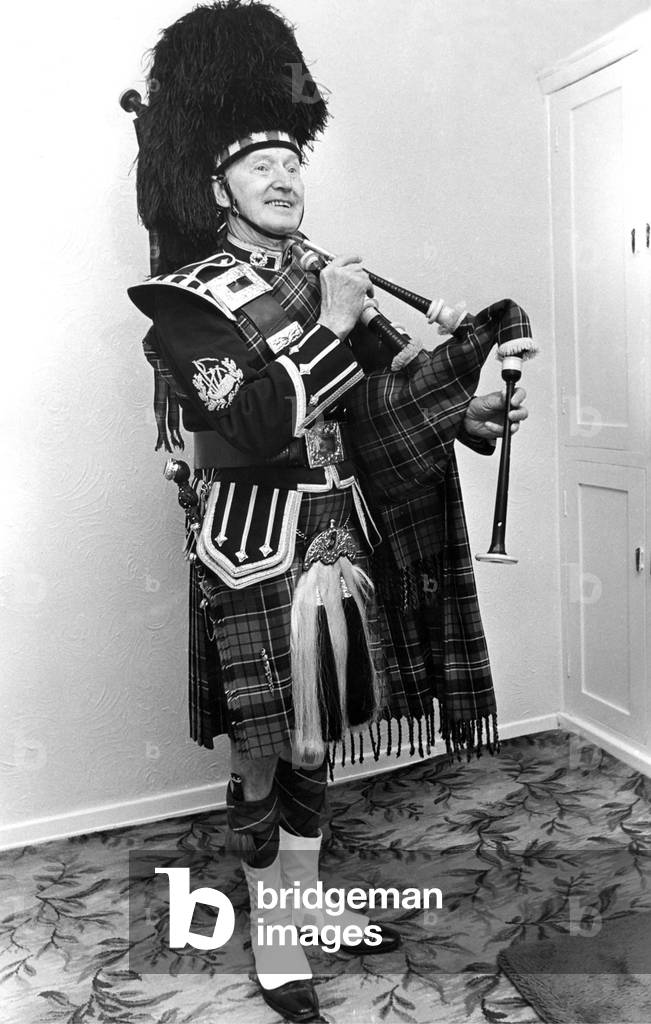 A piper smartly dressed in his uniform and ready to play the bagpipes in March 1982 02/03/1982 (b/w photo)