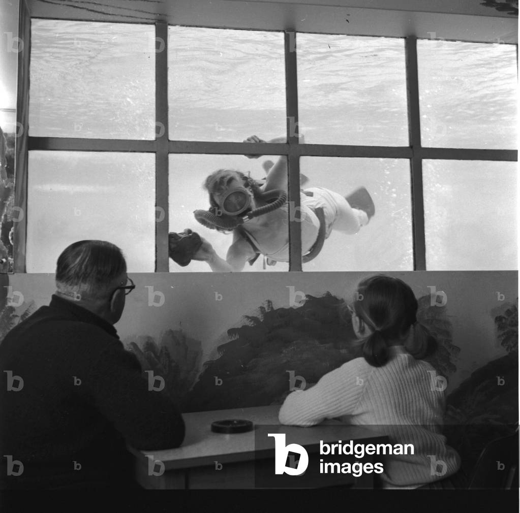 Spring Cleaning at Butlins Cliftonville A member of the Butlins staff keep campers amused as she cleans the windows of the Indoor pool, c, 1955 (b/w photo)