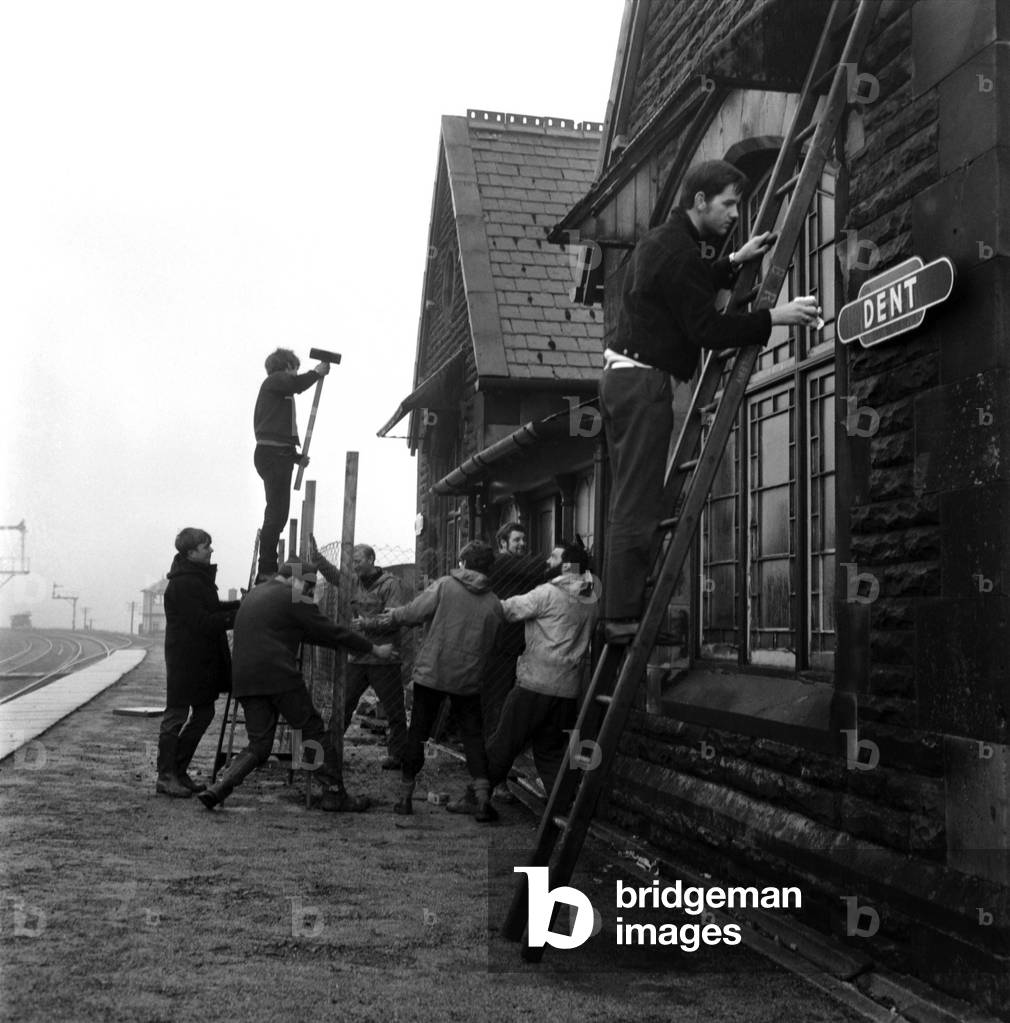 Transport. Rail. Funds raised by selling knickers and bras has helped schoolboys to acquire their own railway station. Boys from the Barden Country Sec School, Burnley, Lancs are now spending their spare time renovating and converting the station at Dent, near Sedbergh, Yorks. Boys building the fence as Lewis Welsh cleans the Dent Sign. December 1967