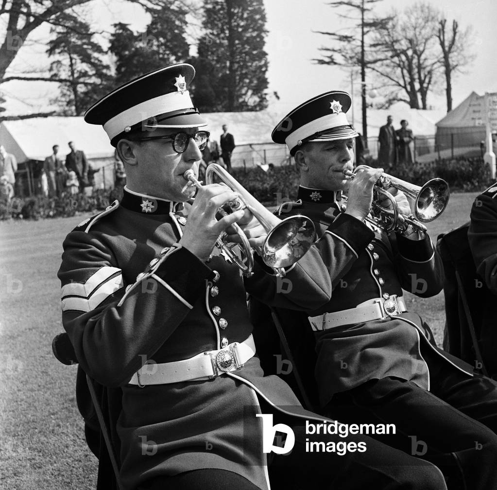 Listening to the band... It's an old British custom, and a good way of taking the weight off your feet. All you need is a deckchair - and an away from it all sense of laziness. The bandmaster tirelessly urges on his men. And if you are in the audience - well, everyone knows that there is joy in seeing someone else work. Chessington, London, 24th April 1954 (b/w photo)