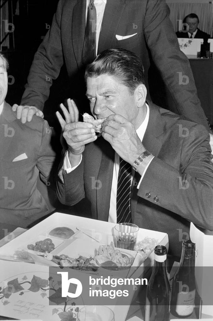 The Institute of Directors annual conference at the Albert Hall, more improperly known as 'The Picnic' from the practice of serving lunch in picnic boxes to the 3,000 odd, directors who attend, was addressed today by such diverse speakers as Barbara Castle, Ronald Reagan, Governor of California, Ian McLeod and John Betjeman. 
Governor Ronald Reagan rejects the knife and fork approach to his cold chicken. 
November 1969