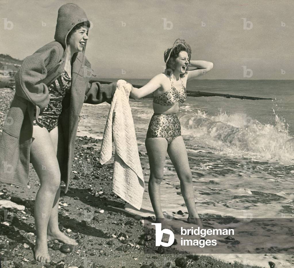 Holidaymakers came in duffle coats over their bathing costumes as they paddle in the sea, March 1948 (b/w photo)