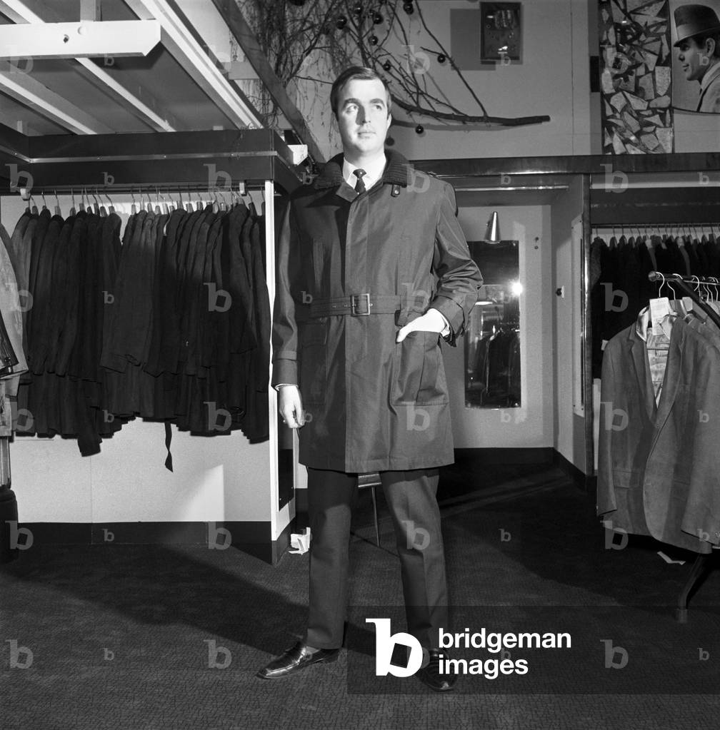 Male model wearing raincoat in menswear department, 1966 (b/w photo)
