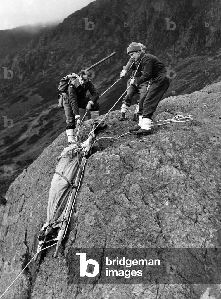 R.A.F. Mountain Rescue Unit Facility Visit for attention of Air Adviser. After attention by the Medical Officer the injured airmen are loweped down precipitous rocks, by the aid of ropes and stretcher, November 1943