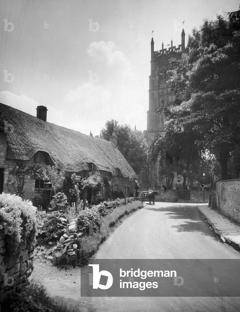 Thatched roof cottages by the churching in the Cotswold village of Chipping Campden, Gloucestershire, c. 1935 (b/w photo)
