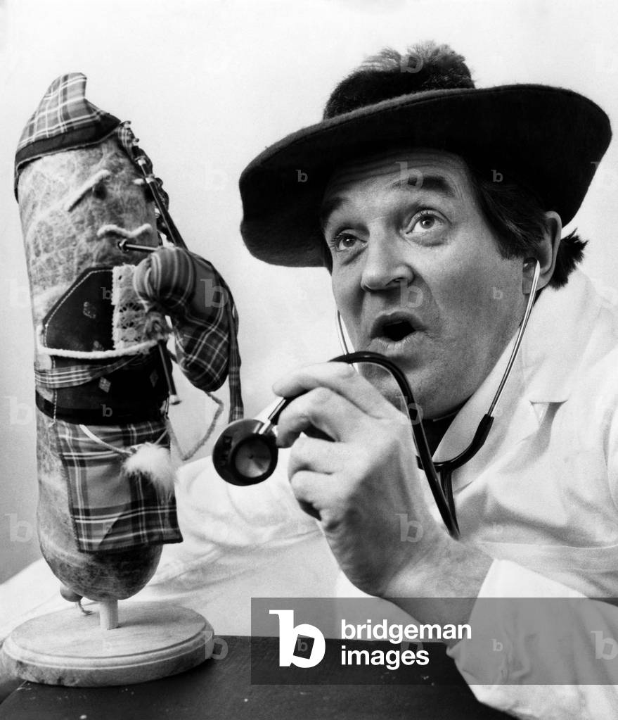 Scots comedian 'doctor' Jimmy Logan giving his Haggis a bit of a medical check-up, to make sure it is 100% fit. January 1976