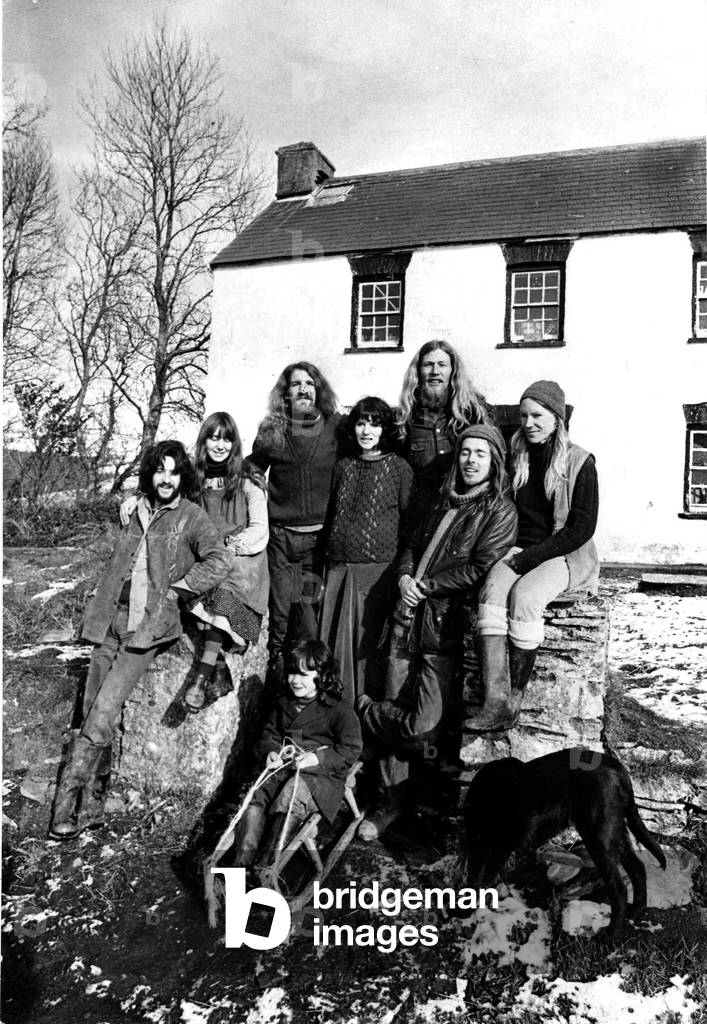 Communes - Eight members of the commune pose in the sunshine outside their farmhouse at Gilfach-y-Bettws, in Carmarthenshire, 15th February 1973 (b/w photo)