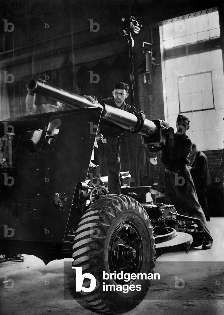 Formation of the Corps of Electrical and Mechanical Engineers. One of the biggest depots is in the Western Command where both soldiers and civilians are employed. Lifting a 25 pounder piece into position after being repaired, September 1942 (b/w photo)
