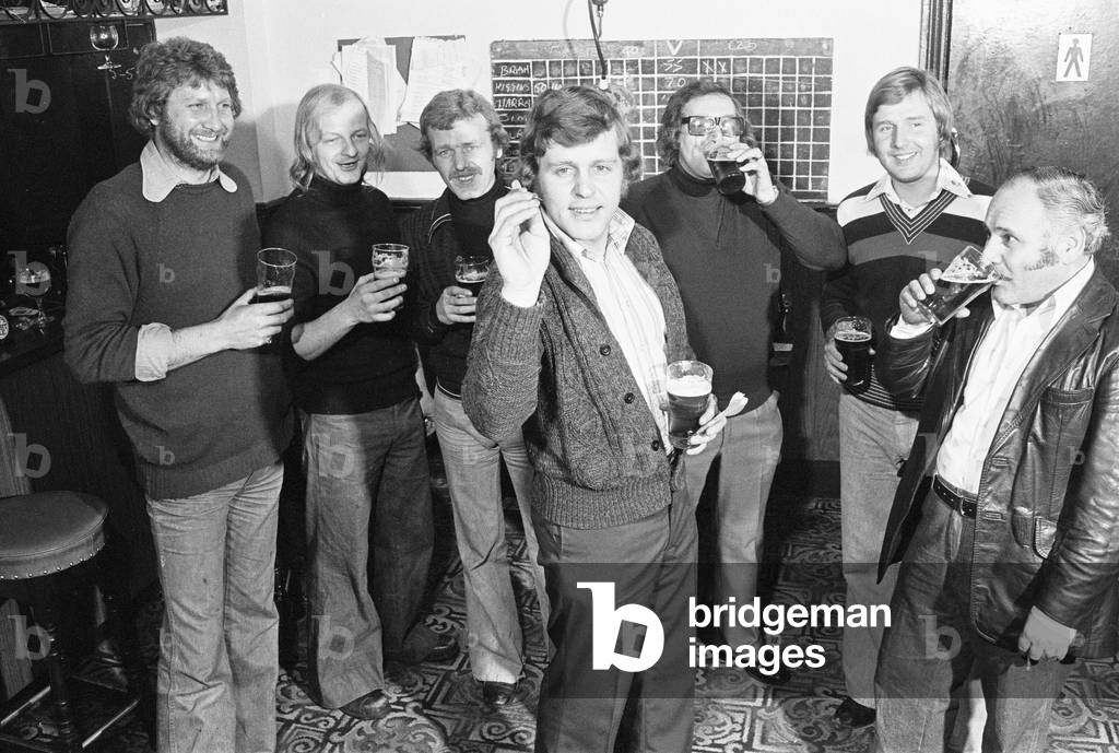 Regular customers at the New Cresta club in Solihull, West Midlands, enjoying a pint during a game of darts. 
25th March 1977.