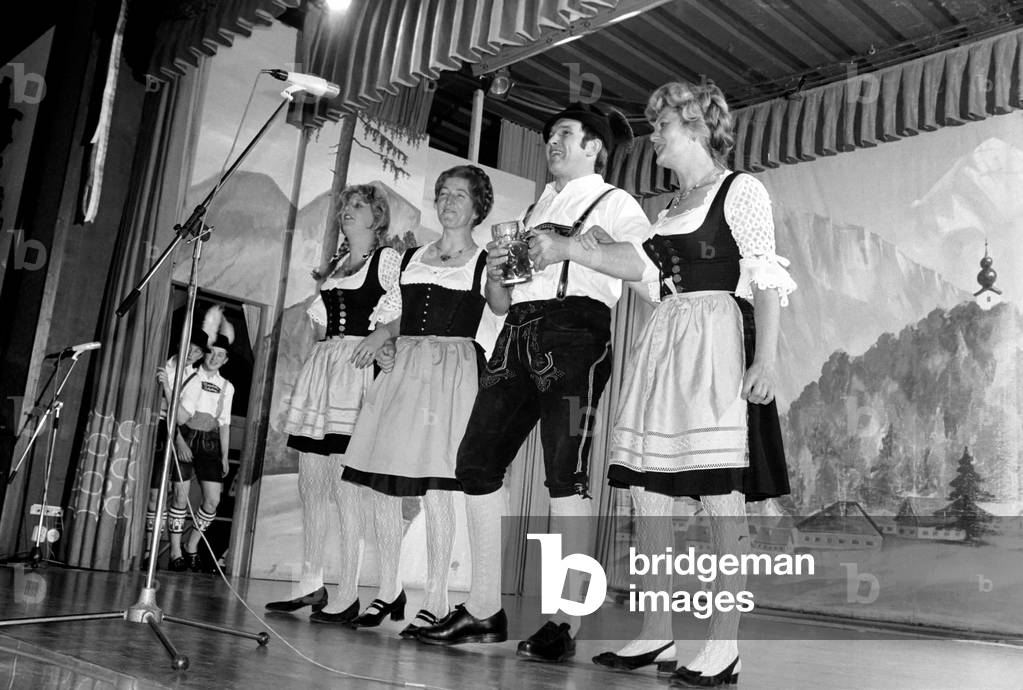 Members of a Bavarian band performing on stage wearing traditional Bavarian dress during a night out in Ruhpolding near Munich, May 1975 (b/w photo)