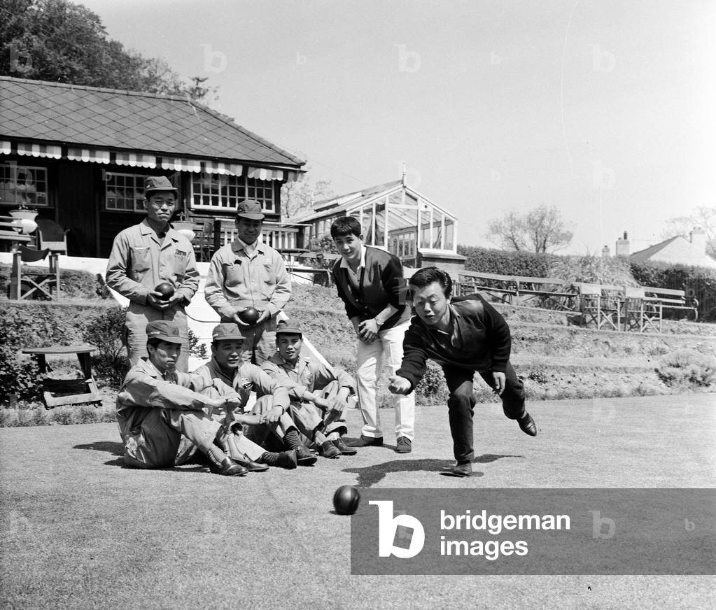 Japanese rider Shimazaki playing bowls with his team of mechanics watching. 5th June 1962 (b/w photo)