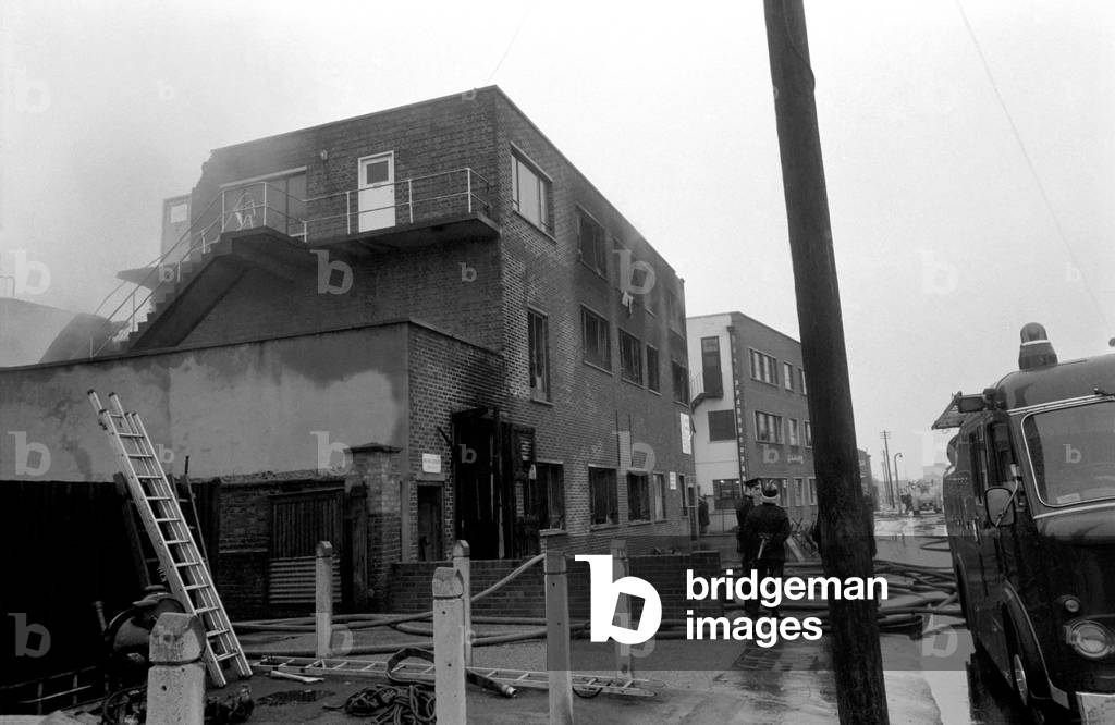 Three firemen were trapped early today, when the roof of a blazing plastics factory in Bond Road, Mitcham, collapsed on them. Firemen still work on the factory 12 hours later. December 1969