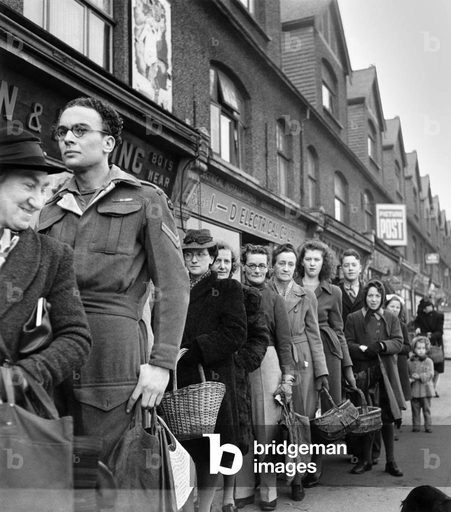 The corporal queues up on leave - It's just the same when you come on leave. Only it's not the Naafi, and it's not a mug of tea at the end of it. 1946 P18776