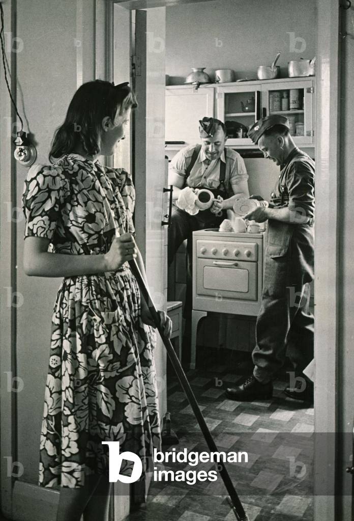 Canadian soldiers washing-up while english woman sweeps floor
Circa 1940