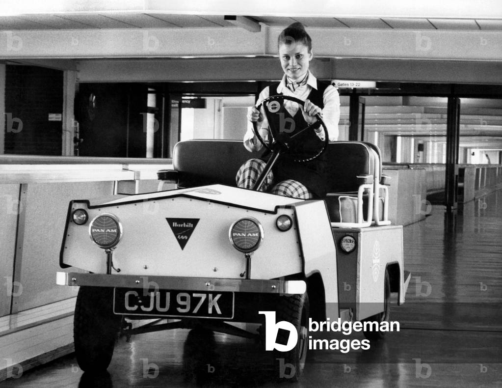 With a view to helping aged and infirm passengers on the often considerable walks along corridors at London's Heathrow Airport, Pan-American airlines are carrying out evaluation trials on this new trolley. Based on a golf trolley, the Harbilt 600 vehicle has a six miles-per-hour speed limit. At the wheel, here, is Pan-Am ground hostess Irene Haines. 
March 1972