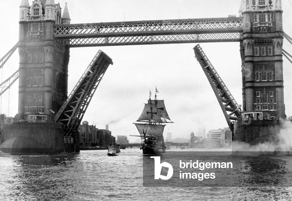 A replica of Francis Drake's ship The Golden Hinde sails down the River Thames from the Pool of London firing several of her 18 cannons as she passes under Tower Bridge, 22nd September 1974 (b/w photo)