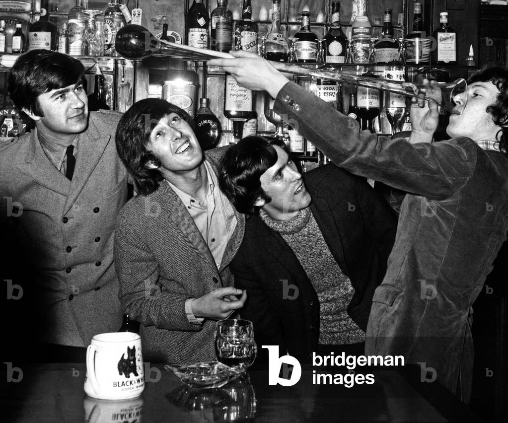 Steve Winwood with the Spencer Davis Group celebrating his by 18th Birthday drinking a yard of Ale at the Shakespeare pub in the West End. l-r Peter York, Spencer Davis and Muff Winwood, 13th May 1966 (b/w photo)