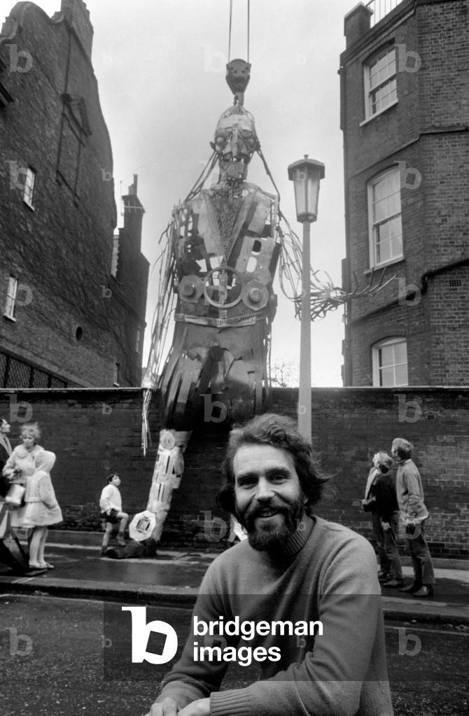 Gulliver, all 21ft of him, weighing 6cwt, made of metal, needed a crane to start him on his journey from Cheyney Walk in Chelsea to Tokyo, Japan. Gulliver is the metal creation by cartoonist, artist, Gerald Scarfe and is one of twelve characters that Gerald is making for the British Pavilion at the Expo '70 to be held in Tokyo in March. The metal monster took Gerald three months to put together, using welding apparatus, he made is in the garden of his home in Chelsea in two halves and each half had to be hoisted by crane from the garden, over two garden walls to the side road where it was packed away into large crates. The other characters that Mr. Scarfe will be working on are Hamlet, MacBeth, Robinson Crusoe, Samuel Johnson, Long John Silver, Pick Wick, Alice 'thru the looking glass, Oliver, Shakespeare, James Bond and My Fair Lady. Bearded Gerald Scarfe with Gulliver. December 1969