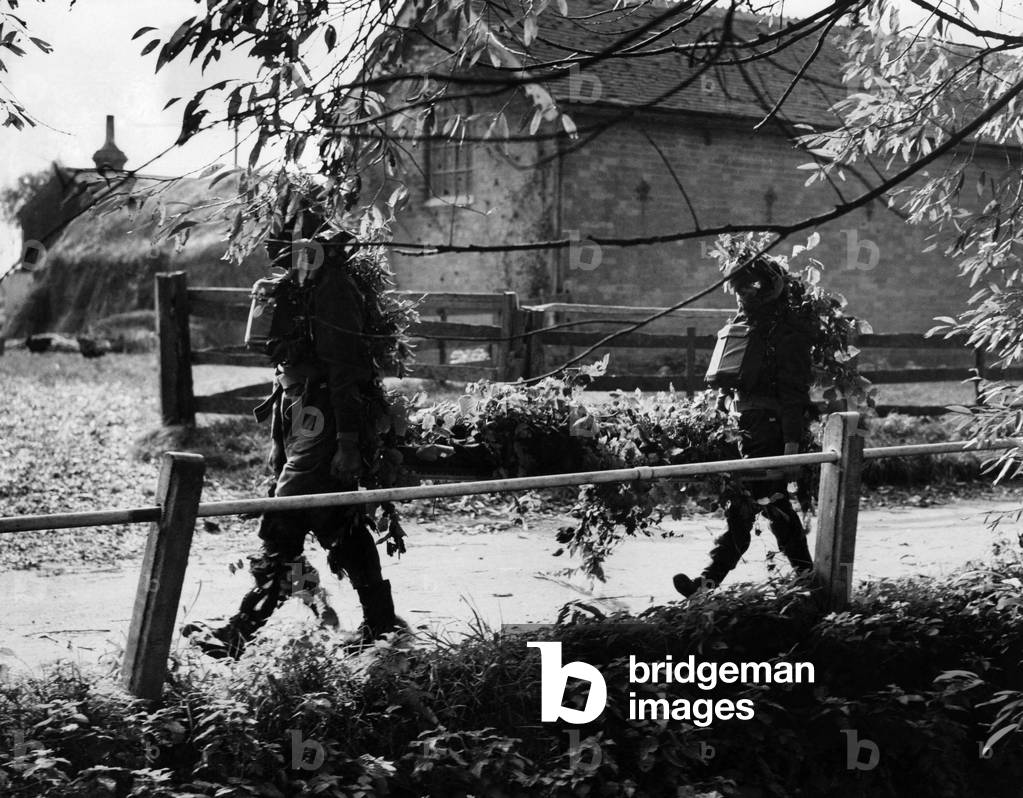 RAMC Stretcher bearers show how to camouflage themselves and their casualty with branches of trees evade capture October 1941 (b/w photo)
