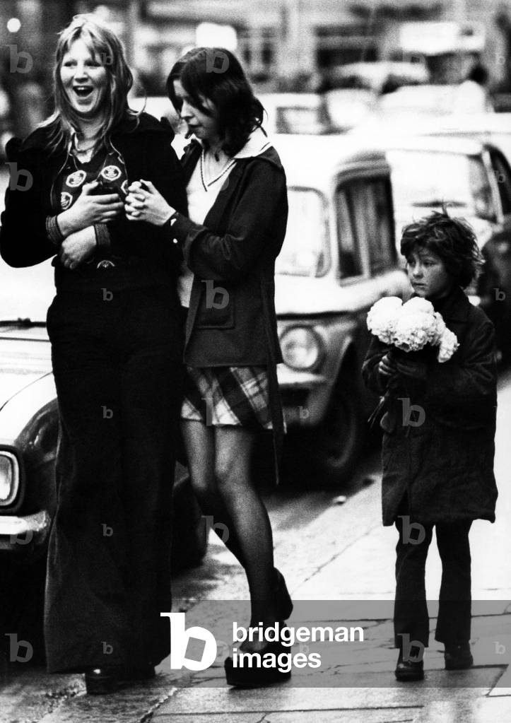 A child selling paper flowers on the streets of Newcastle on 27th December 1974 (b/w photo)