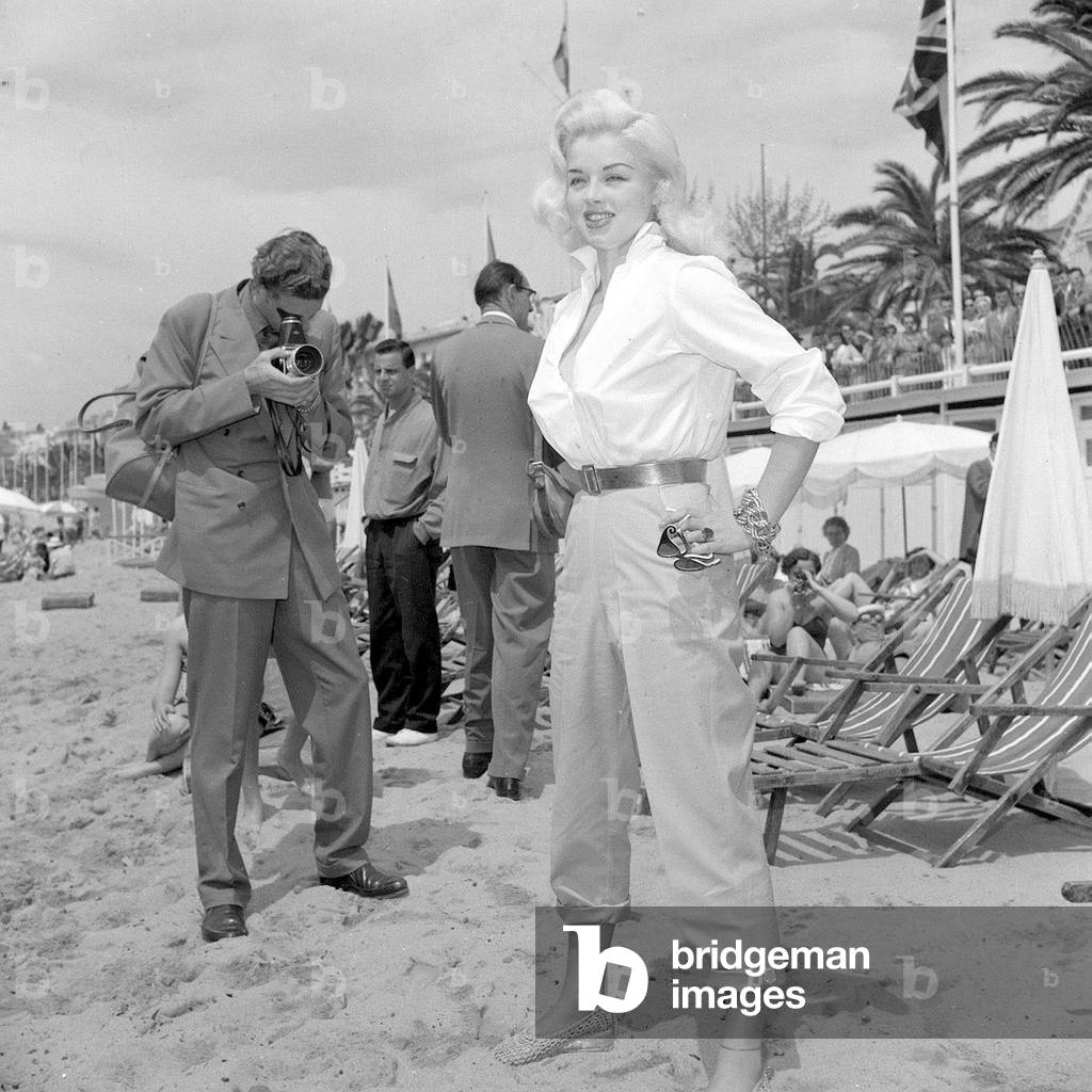 Actress Diana Dors has her picture taken by a photographer on the beach at Cannes Film Festival, May 1956 (b/w photo)