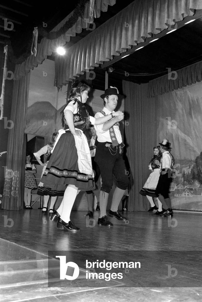 Bavarian couples in traditional dress dancing on stage during a night out in Ruhpolding near Munich, May 1975 (b/w photo)