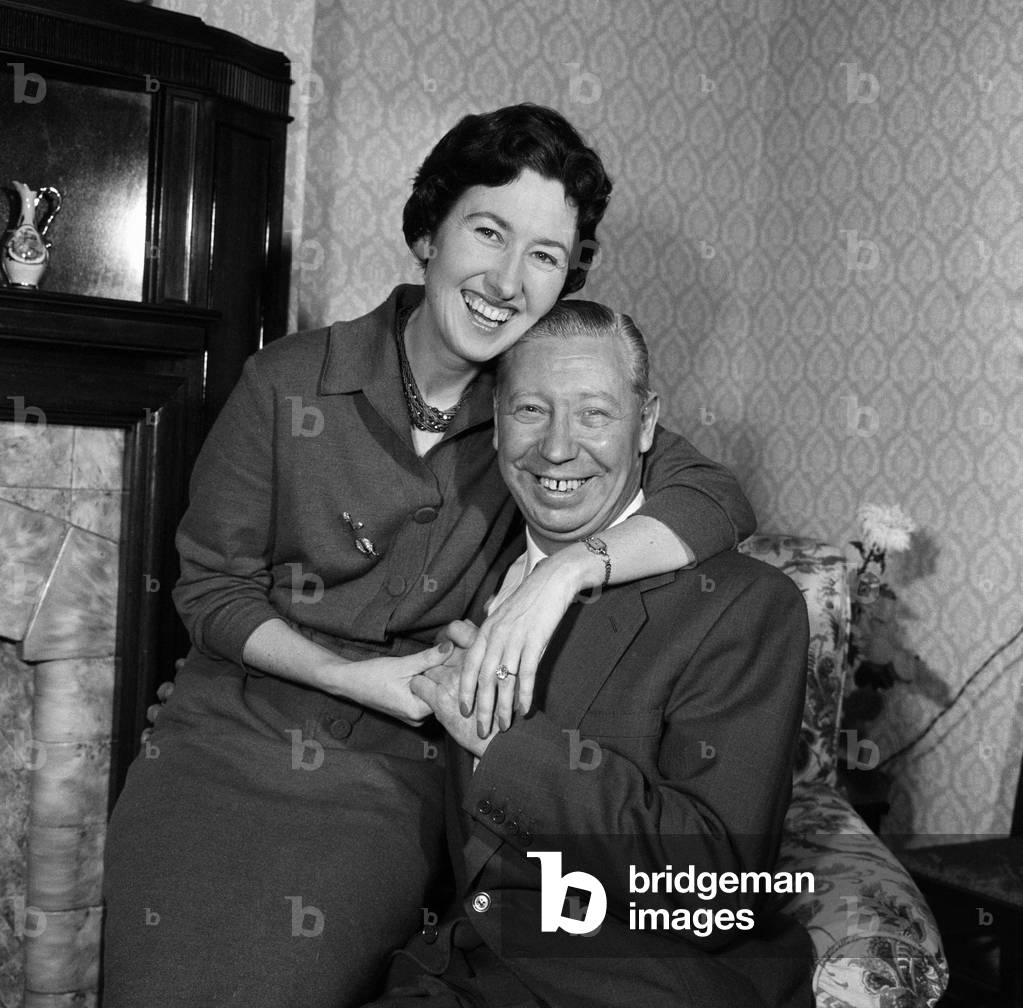 George Formby and fiancee Pat Howsen of Preston pictured at her home last night. She is wearing the huge solitaire diamond ring on her engagement finger. George is wearing his usual smile. 13th February 1961 (b/w photo)