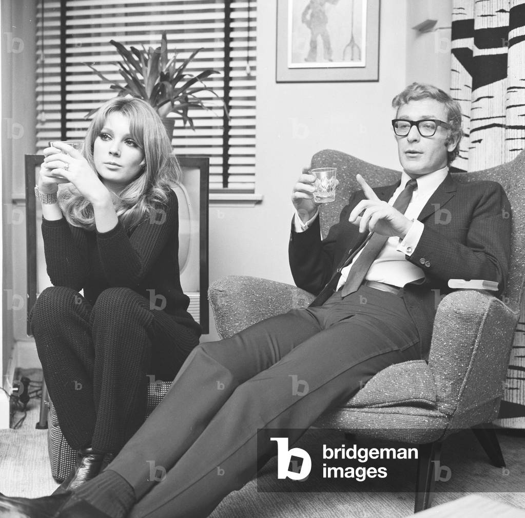 Actor Michael Caine pictured with French actress Miss Elizabeth Ercy in the flat of the Mirror's Donald Zec. 
2nd December 1965.