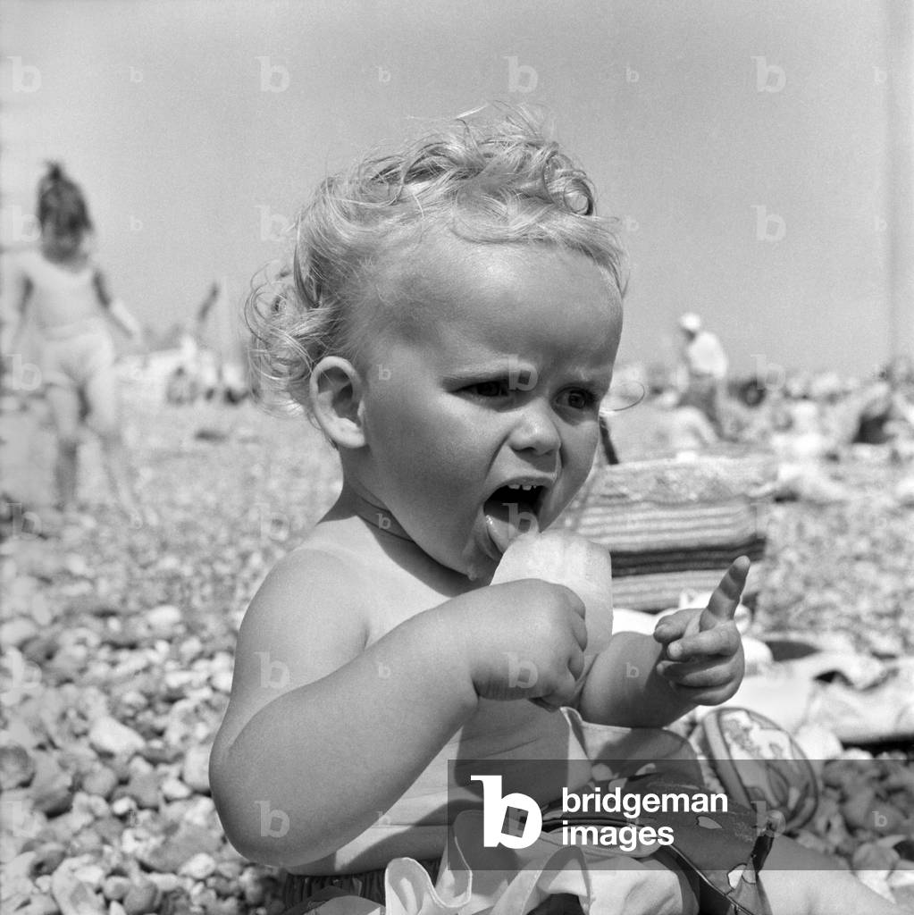 Baby and Lolly. Derorah Ann Clowes 13 months from Stoke on treat enjoys herself in the beach with her lolly. June 1960 M4270-008